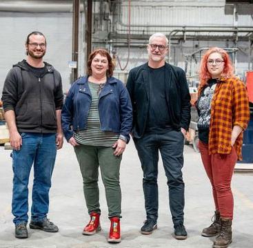 four people st和ing next to each other in a foundry